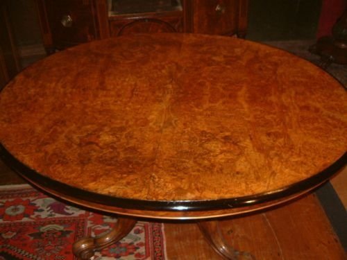 victorian oval dining table with burr walnut top supported on a well carved pedestal